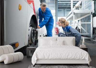 mechanic showing apprentice how to tighten nuts on bus wheel Wall mural