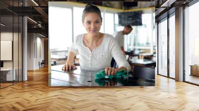 portrait of smiling waitress cleaning bar counter in bar Wall mural