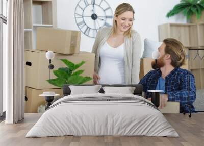 pregnant couple talking while preparing boxes Wall mural