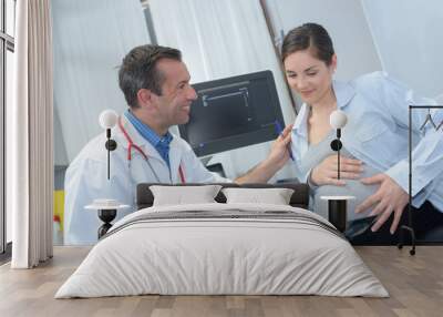 pregnant woman consulting male doctor white sitting in clinic Wall mural