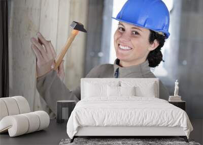 pretty young woman hammering nail into wall Wall mural