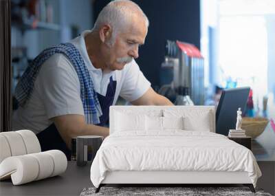 senior man barista using laptop Wall mural