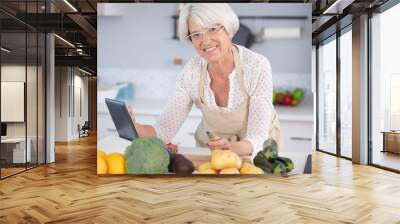 senior woman cooking with help of recipe on tablet Wall mural