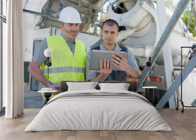 two male workers looking at tablet next to cement lorry Wall mural