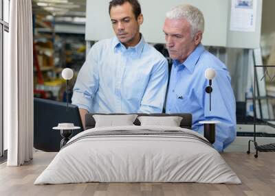 two management level workers looking at laptop in factory Wall mural