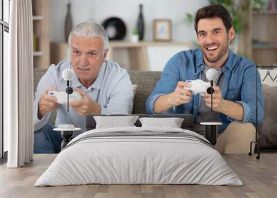 two men sitting on the sofa and playing video games Wall mural