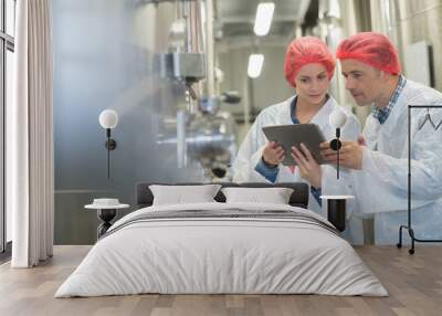 two quality control workers wearing hairnets looking at digital tablet Wall mural