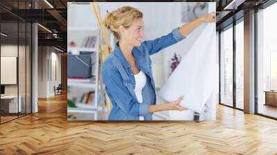 woman unrolling a wall paper on the wall Wall mural