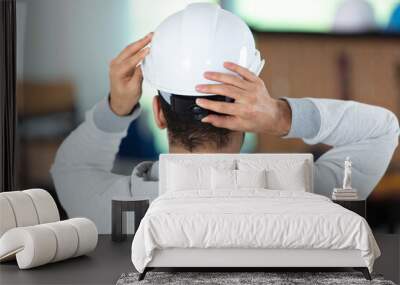 workman adjusting his hard hat to fit correctly Wall mural