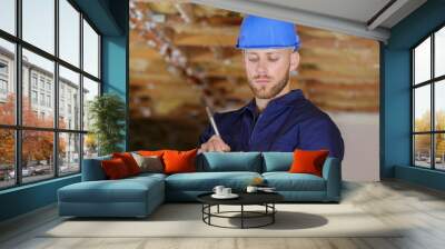 young builder in property writing on clipboard Wall mural