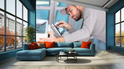 young male technician is repairing a printer at office Wall mural