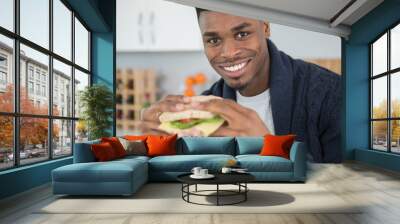 young man eating a sandwich at home Wall mural