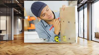 young man marking position on cupboard he is assembling Wall mural