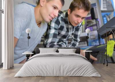 young men looking at synthesizer in shop Wall mural