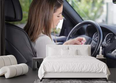 young woman taking pill on drivers seat of car Wall mural