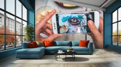 hands hold the phone, photographing colorful, healthy food on a light wooden table Wall mural