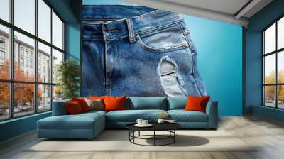 Close up of distressed denim jeans on a blue background Wall mural