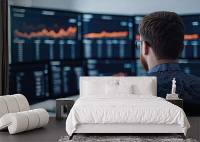 Businessman analyzing data on multiple monitors, showcasing financial trends and metrics for informed decision-making. Wall mural