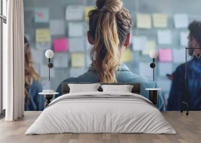 A woman with a ponytail stands in front of a white board with a lot of notes on it. She is looking at the board with a serious expression Wall mural