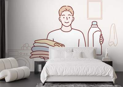 man holding folded clothes and detergent bottle at laundry roomHand drawn style vector design illustrations. Wall mural