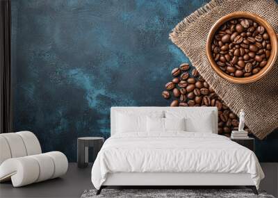 Close-up of roasted coffee beans in a burlap sack on a rustic blue surface.
 Wall mural