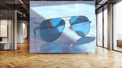 a pair of cool blue sunglasses on a light surface Wall mural