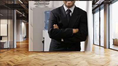 Confident businessman with arms crossed leaning on wall Wall mural