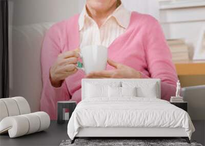 Content senior woman relaxing with tea on sofa at home Wall mural