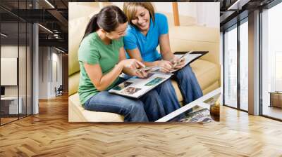 friends sitting in livingroom looking at photograph album Wall mural