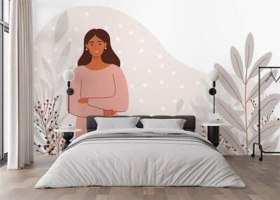 A smiling woman with long brown hair stands confidently with her arms crossed, wearing a pink sweater and black pants, in front of a soft pink background with grey floral accents. . Generated AI Wall mural