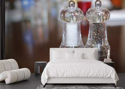 Salt and pepper shakers on a wooden table. Glass salt and pepper in restaurant. Salt and pepper grinder. Wall mural