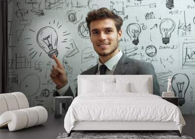 Business sketch and mock up place with an attractive smiling european businessman pointing up at glowing lamp. Idea, energy, inspiration and innovation concept. Wall mural