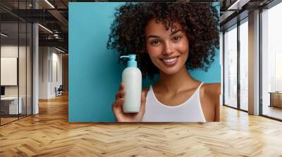 Female holding blank shampoo bottles and conditioners for hair on blue background, smiling woman portrait, bodycare concept of moisturizing spa Wall mural