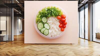 In a beige background, a salad with rice and tomatoes is contained in a plastic container. Wall mural