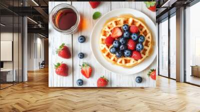 On a white plate are delicious waffles topped with blueberries and strawberries. Wall mural