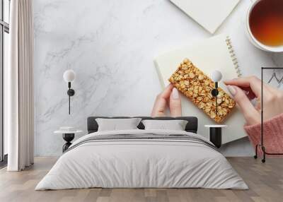 Woman at a light table holding a delicious granola bar while working Wall mural