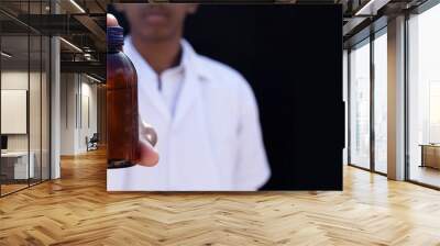 The young doctor holds the urine or other sample on a black background Wall mural