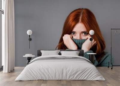 shy or embarrassed woman pulling turtleneck sweater over face Wall mural