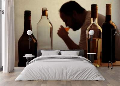 silhouette of anonymous alcoholic person drinking behind bottles of alcohol  Wall mural