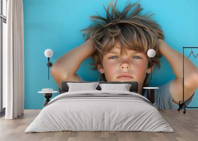 Young boy ruffles his wild messy hair in front of a blue wall. Child model acting as cool kid. Wall mural