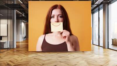 young woman hiding emotion with fake smile drawn on paper Wall mural