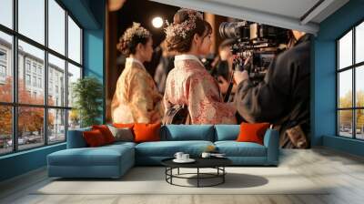 Two women in beautiful kimonos stand still while a cameraman captures their elegant attire against a backdrop of traditional architecture at golden hour Wall mural