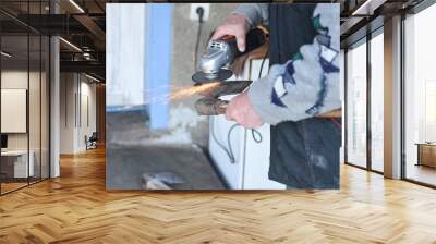 Close up of a man sharpen an ax using electric grinder. Sparks w Wall mural