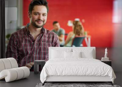 confident male designer working on a digital tablet in red creative office space Wall mural