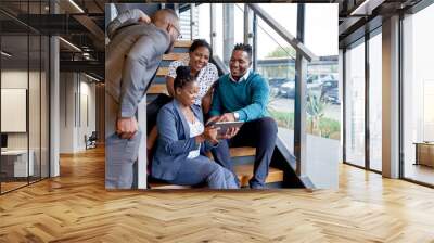 Four professional male and female coworkers sitting on staircase Wall mural