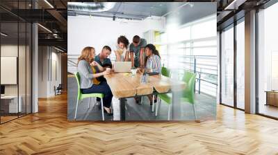 Multi ethnic group of succesful creative business people using a laptop during candid meeting Wall mural