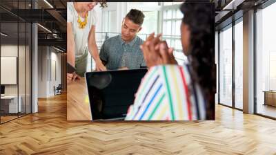 Multi ethnic group of succesful creative business people using a laptop during candid meeting Wall mural