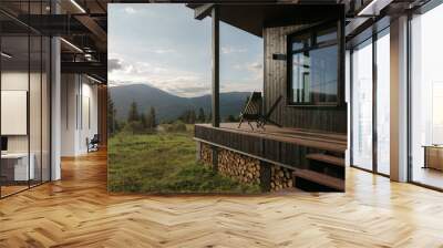 Black wooden chairs on cabin terrace with mountain view at sunset Wall mural