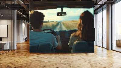 A young couple is having a fun adventure on a road trip through the countryside, driving off-road in their car. Wall mural