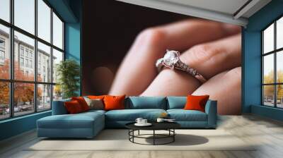 Close up of an elegant engagement diamond ring on woman finger. love and wedding concept. Diamond ring on young lady's hand on dark background, Generative AI Wall mural